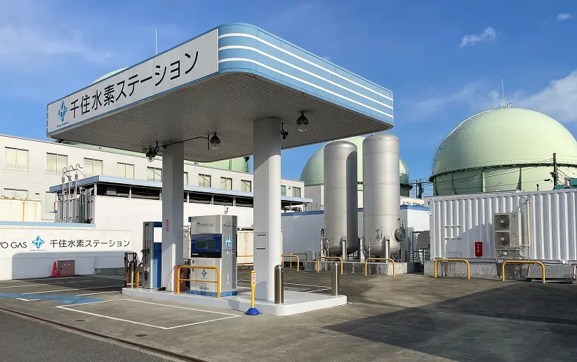 東京ガスの千住水素ステーションの外観。青空の下、水素充填設備と複数のガスタンクが並ぶ清潔な施設。